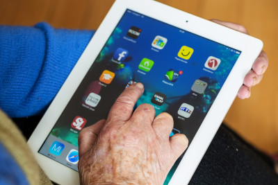 A hand hovers over an iPad with icons visible