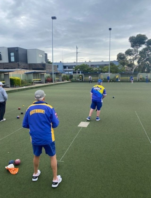 people are bowling down a green away from the camera