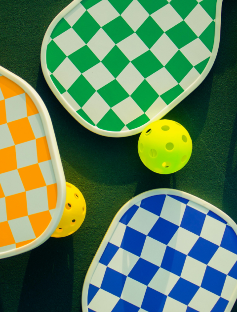 three brightly coloured bats: orange, blue and green and two yellow balls