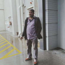 A portrait of a man standing on wet concrete