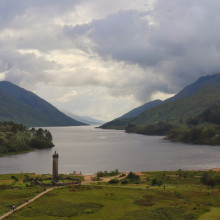 A statue at the edge of a bay closed in by mountains