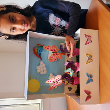 A child poses next to her flower diorama