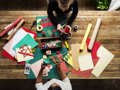 An overhead shot of two people working on different paper crafts