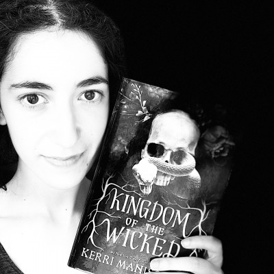 A black and white photo of Emily holding a copy of Kingdom of the Wicked
