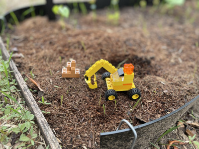 A lego digger in a garden