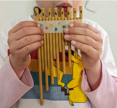 a child is blowing over a pan flute made of straws