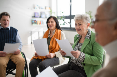 Four people sitting in a circle, holding sheets of paper