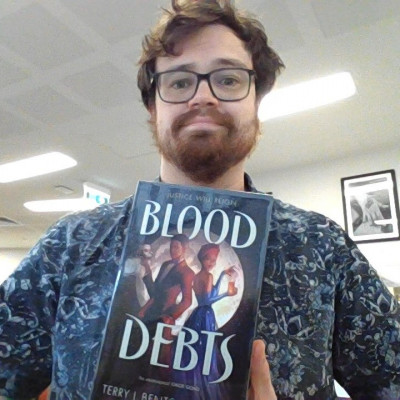Librarian Declan holds a copy of Blood Debts