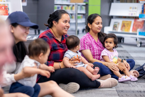 Mothers and children sitting on the floor in the library.