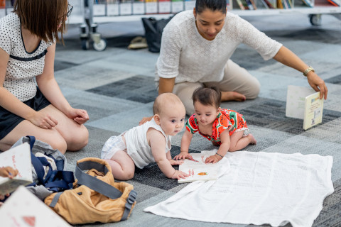 Mothers and babies playing on the floor in the library.