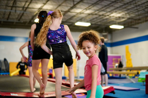 kids are climbing onto gym equipment in a queue and smiling