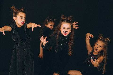 a group of girls are dressed in black with cat make-up and acting at the camera