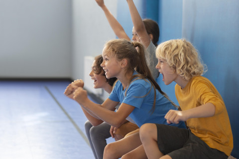 children are doing squats leaning against a wall and cheering