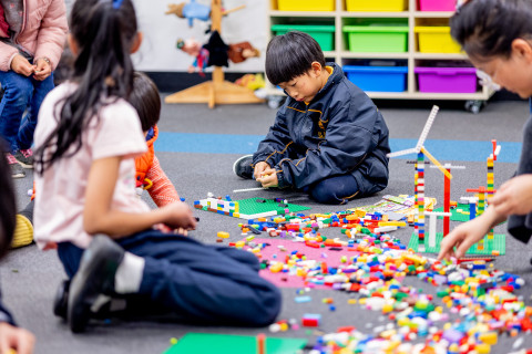 Children and parents sitting on the floor in the library and building with Lego.
