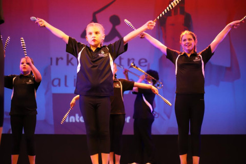 a group of girls dressed in black are standing on a stage with their arms held high