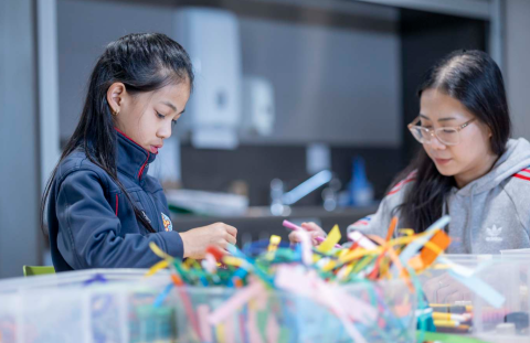 2 people making craft with paper strips