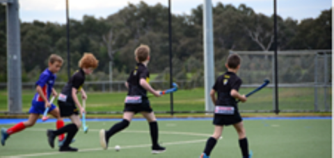 Children participating in a hockey session on an outdoor field
