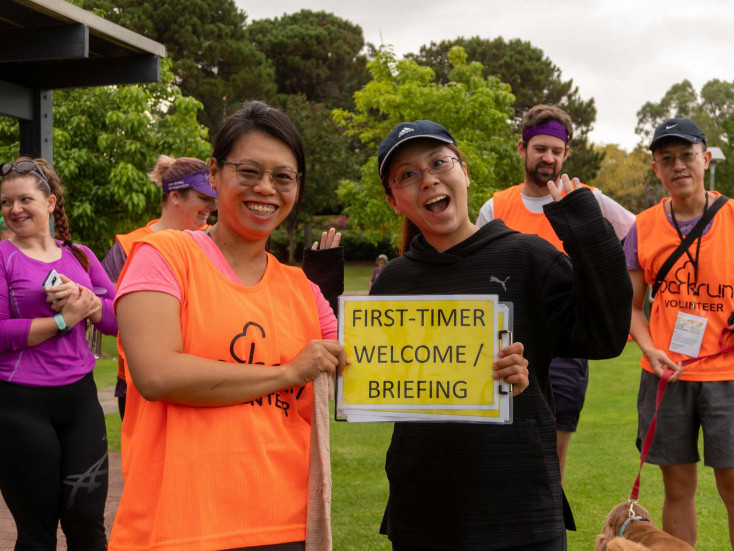 two people holding a sign saying First-time welcome/ briefing