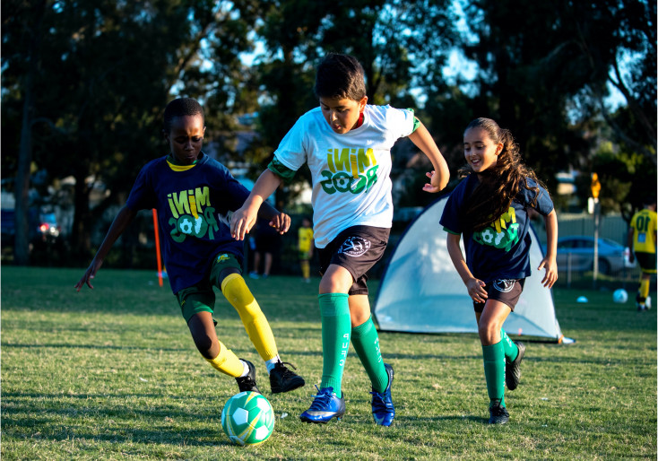 Three children are running after a round football
