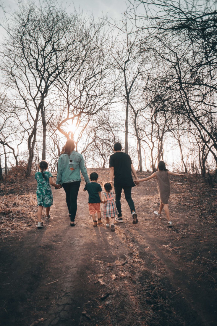 2 adults and 4 children are walking away holding hand Photo by Orlando Allo on Unsplash