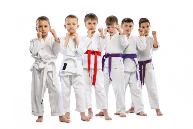 a group of boys and girls stand wearing a karate outfit