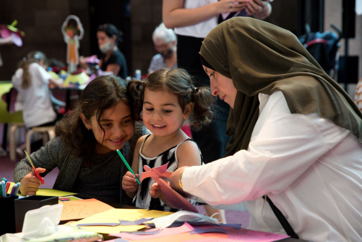 A mother helping her children make a paper craft.