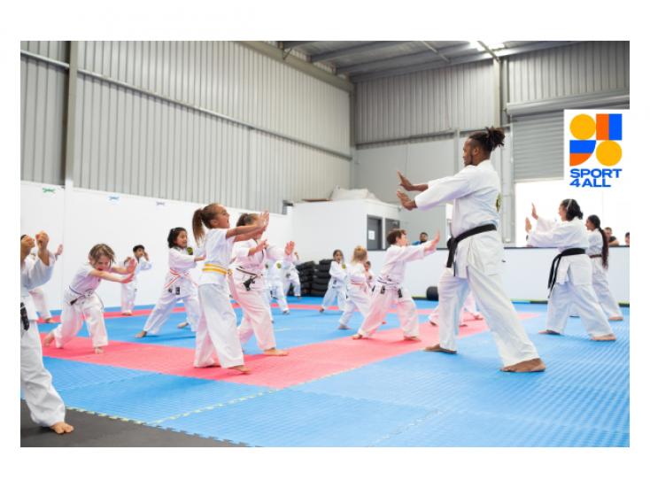 a group of people wearing karate uniforms are facing an instructor