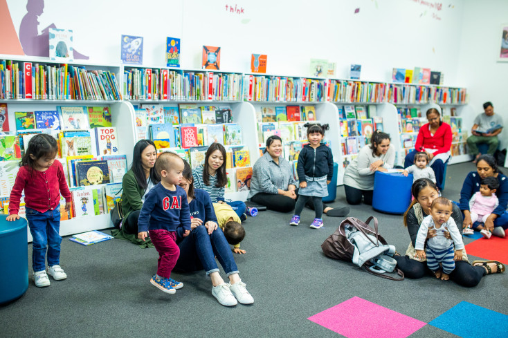 Children and parents sitting on the floor in the library.