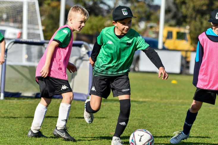 two children are running towards a football
