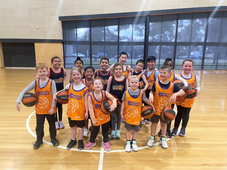 a group of kids wearing yellow basketball vests are smiling at the camera