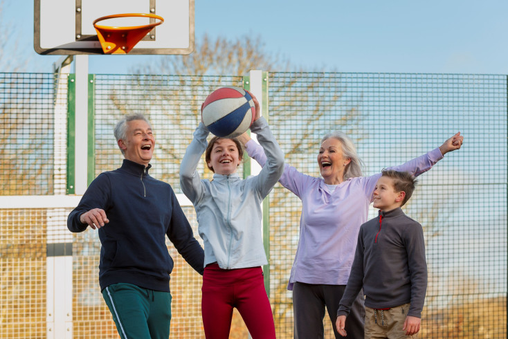 two young kids and two grandparents are cheering and holding a basketball