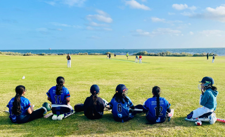 a group of kids are sitting waiting to play cricket