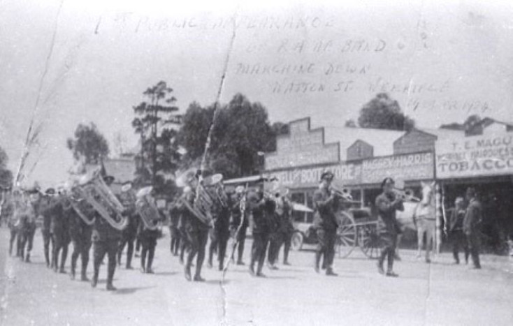 A black and white photo of the RAAf band marching down Watton Street in 1923, with shop front visible n the background and some faint writing on the top of the image.  