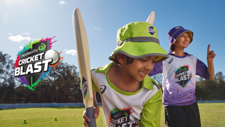 a kids is preparing to hit a ball while another kids cheers in the background