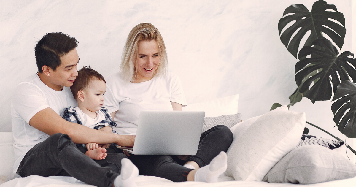 A man, woman, and baby look at a laptop