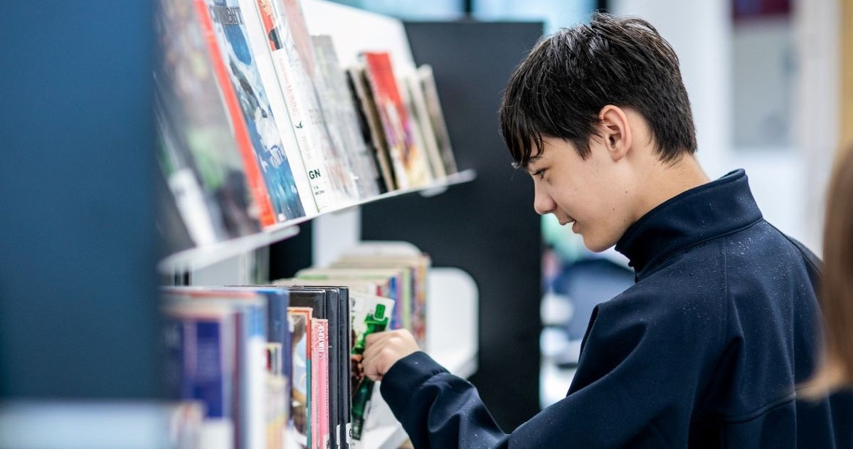 A young man looks through the library shelves
