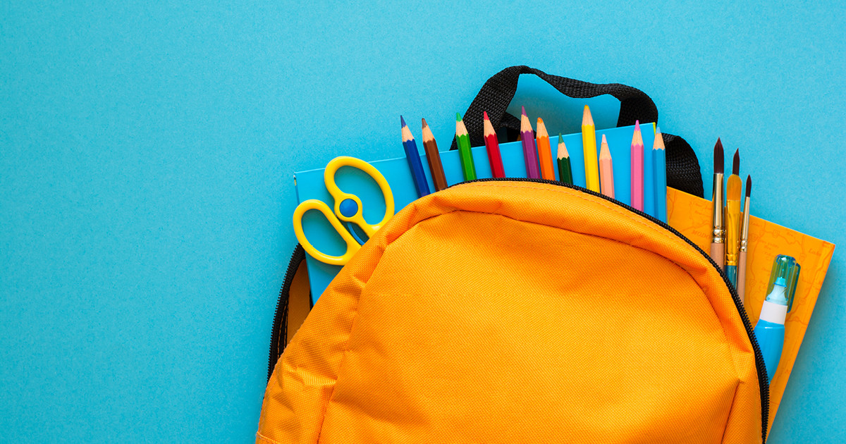 An orange backpack with pencils and tools showing, on a blue background