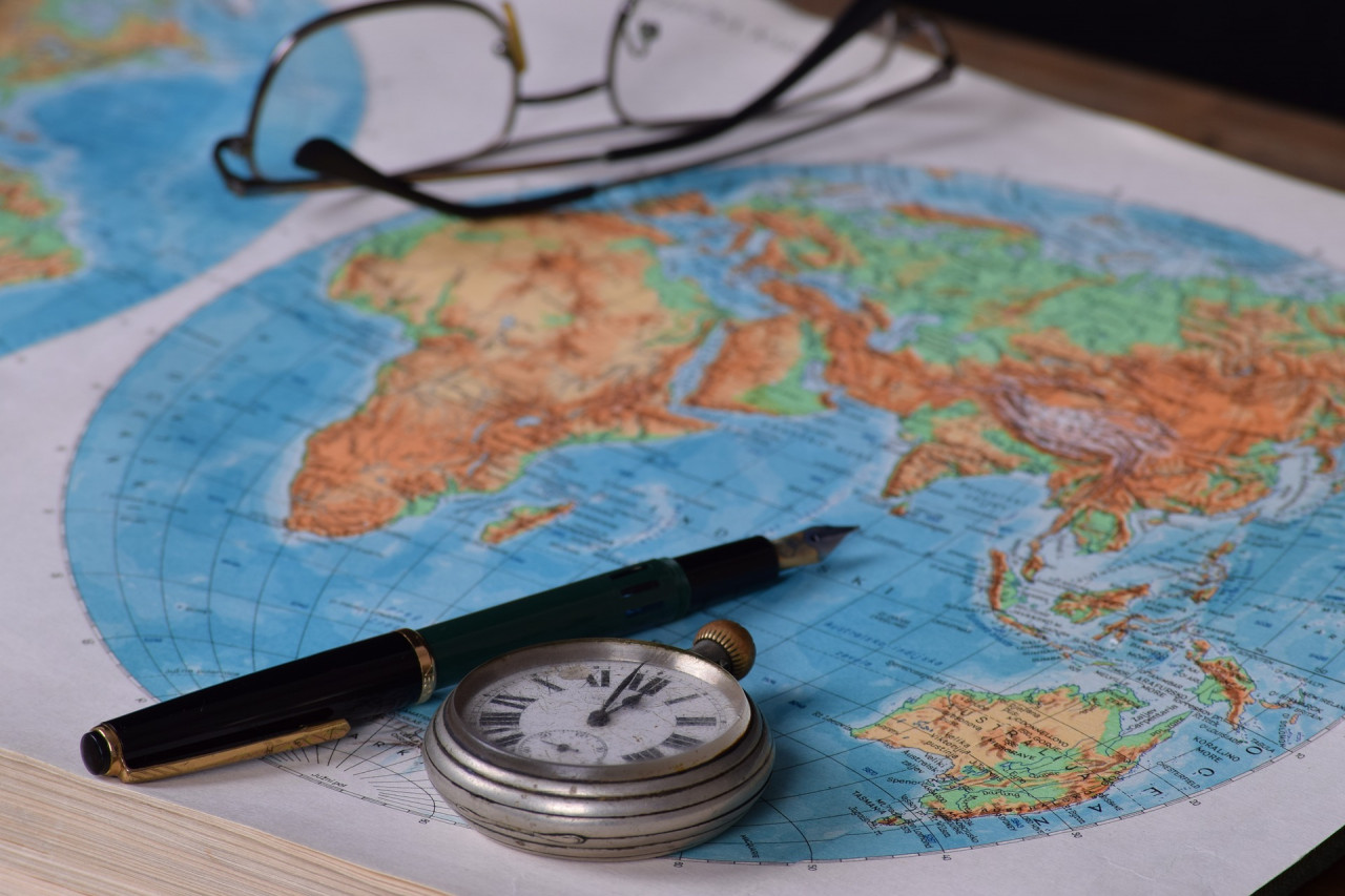 Glasses, a pen, and a pocketwatch on a world map
