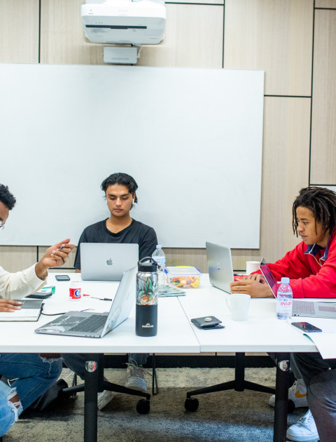 Four young people work at a desk