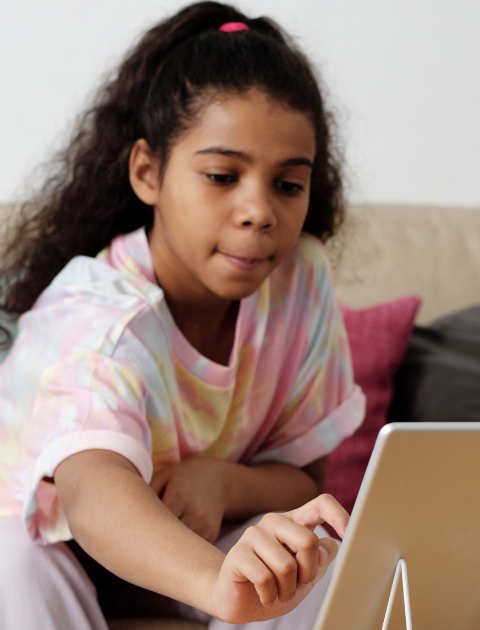 A child reaching towards a tablet on a stand
