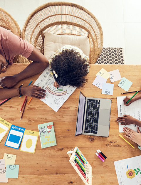 A family sits around a kitchen table, working on homework together
