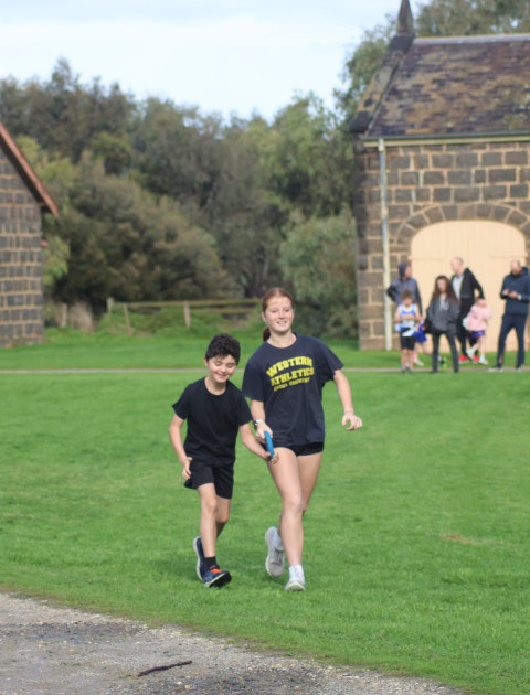 two children are running together, they are both holding a guiding strap