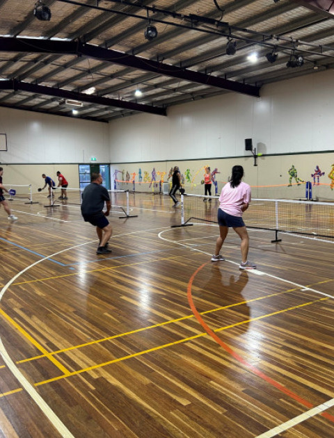 a group of people are playing pickleball indoors