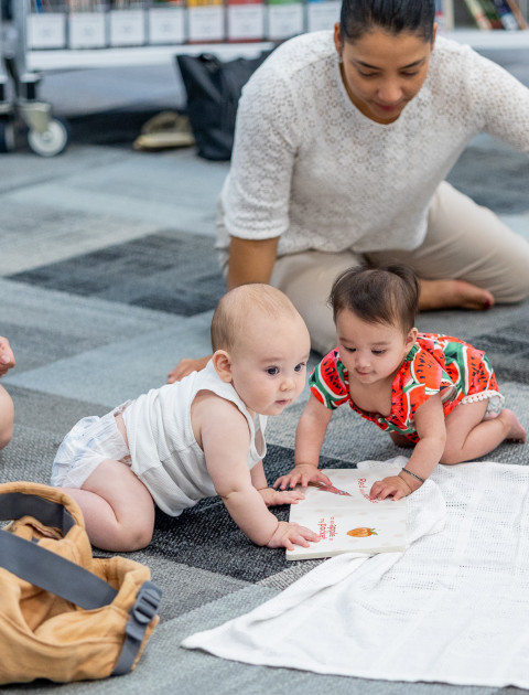 Mothers and babies playing on the floor in the library.