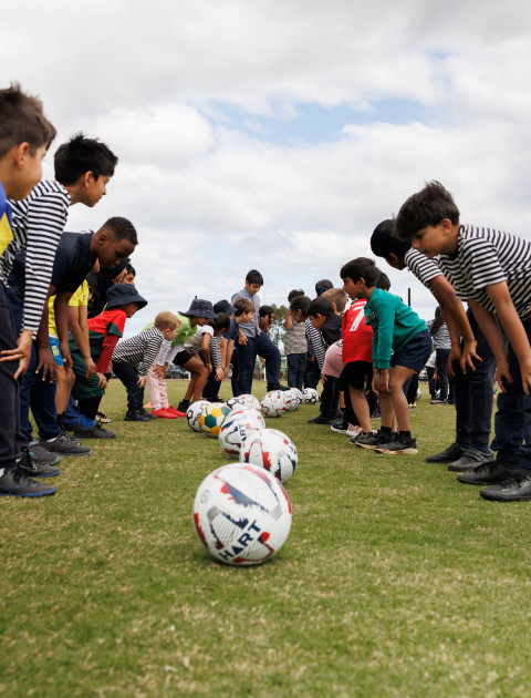 two children in lines facing each other are watching a white football