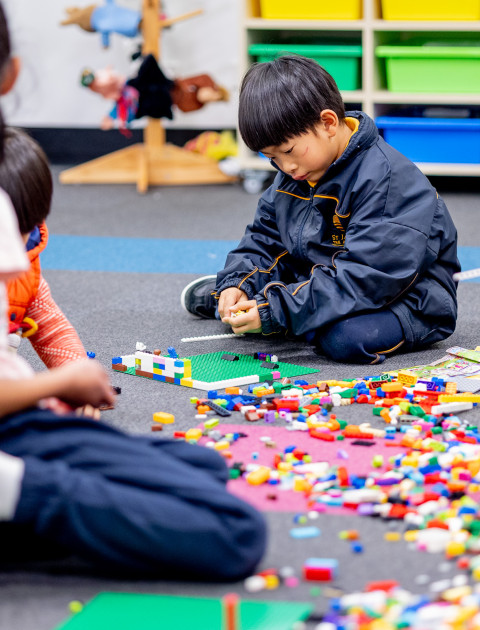 Children and parents sitting on the floor in the library and building with Lego.