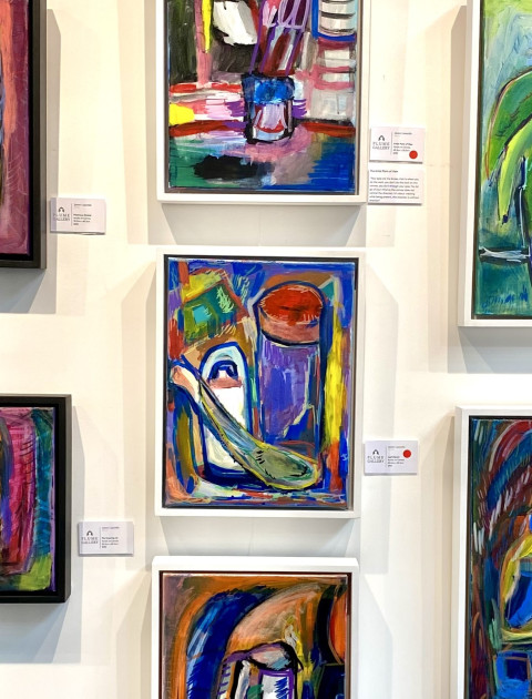 Close-up photo of 6 colourful paintings by local artist James Lazaridis, displayed on a wall.