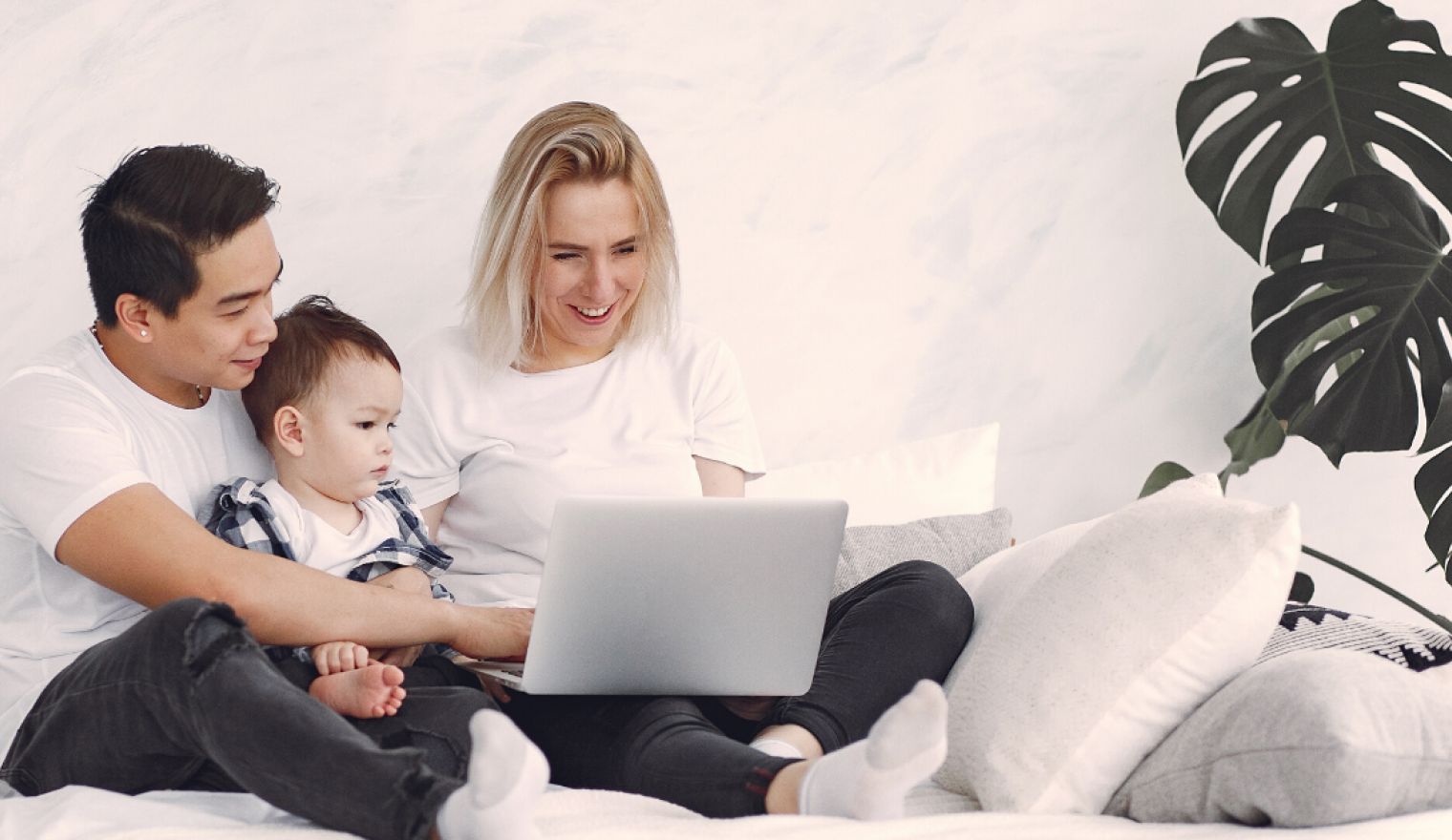 A man, woman, and baby look at a laptop
