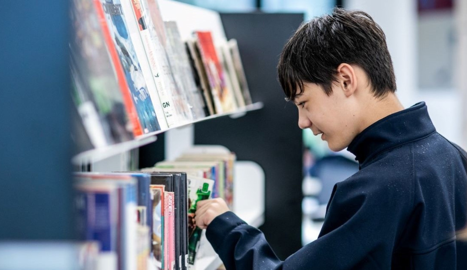 A young man looks through the library shelves