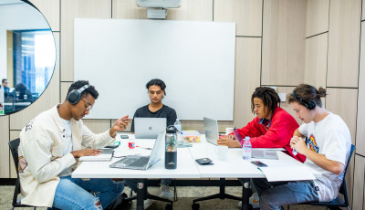 Four young people work at a desk